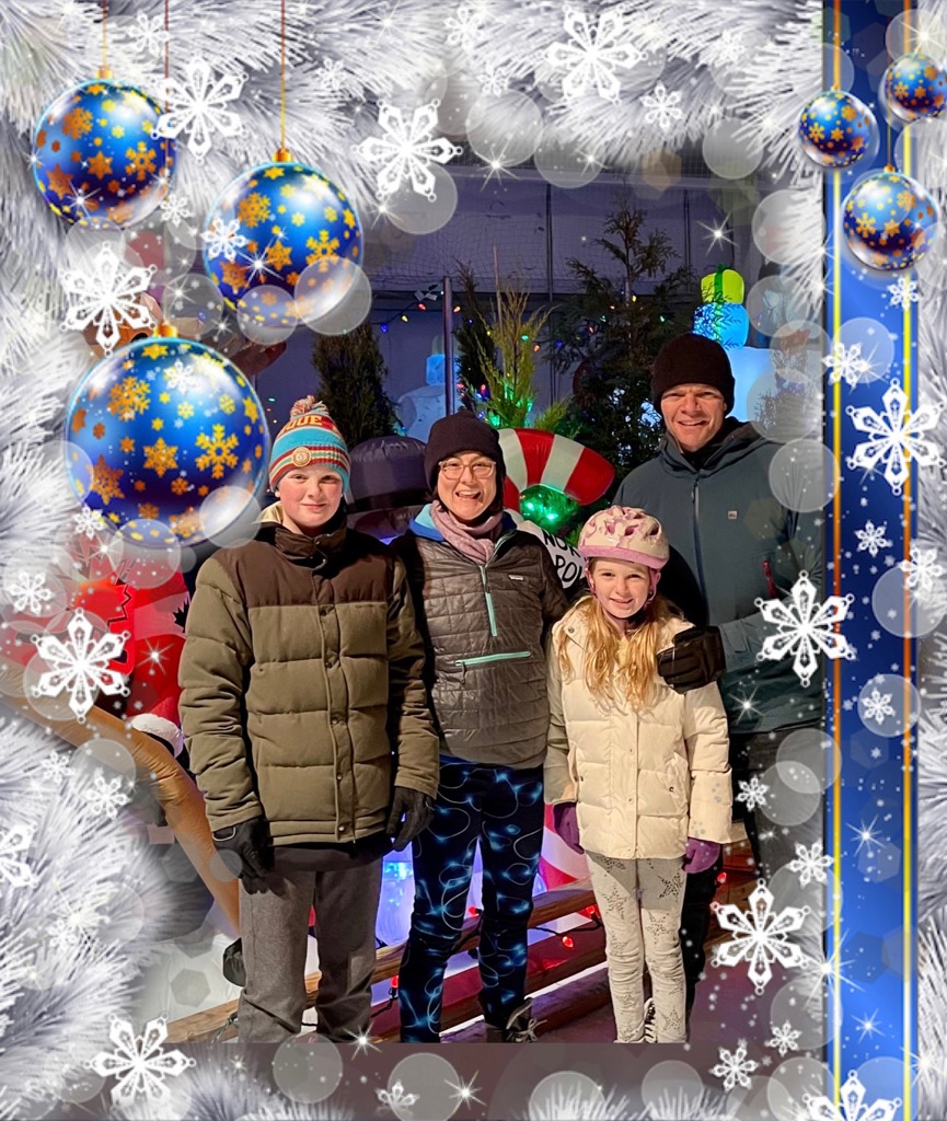 Dean stands with his family in winter attire, surrounded by a white digital wreath and ornaments.