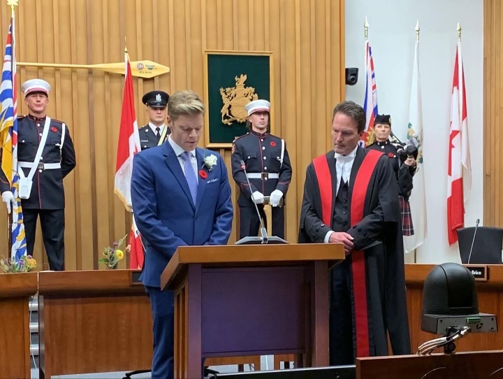 Dean looks down at a podium in the Saanich council chambers as he is sworn in as Mayor.